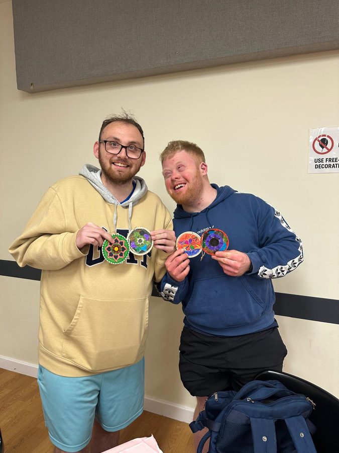 Two members proudly showing off the mandala crafts they made